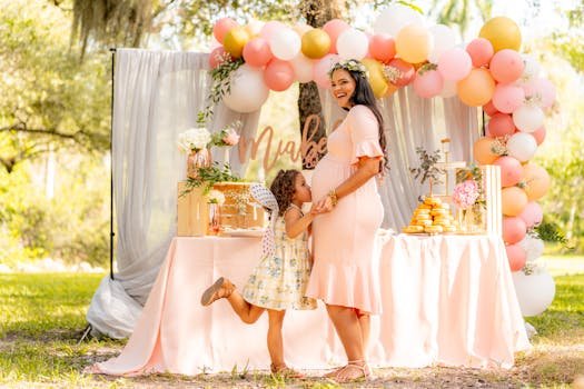 A cheerful outdoor baby shower with a mother and daughter by a decorated table.